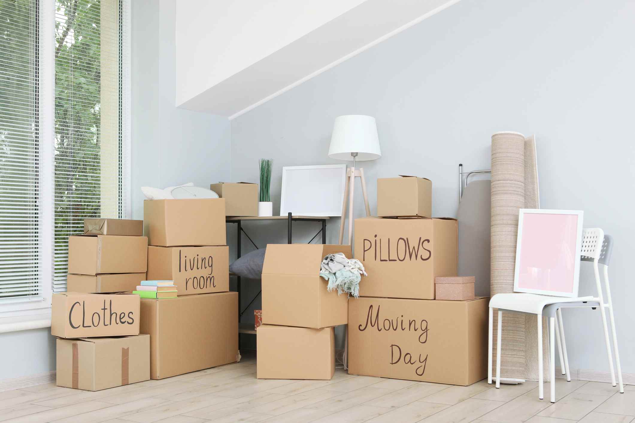 Cardboard boxes and household stuff in empty room. Moving day