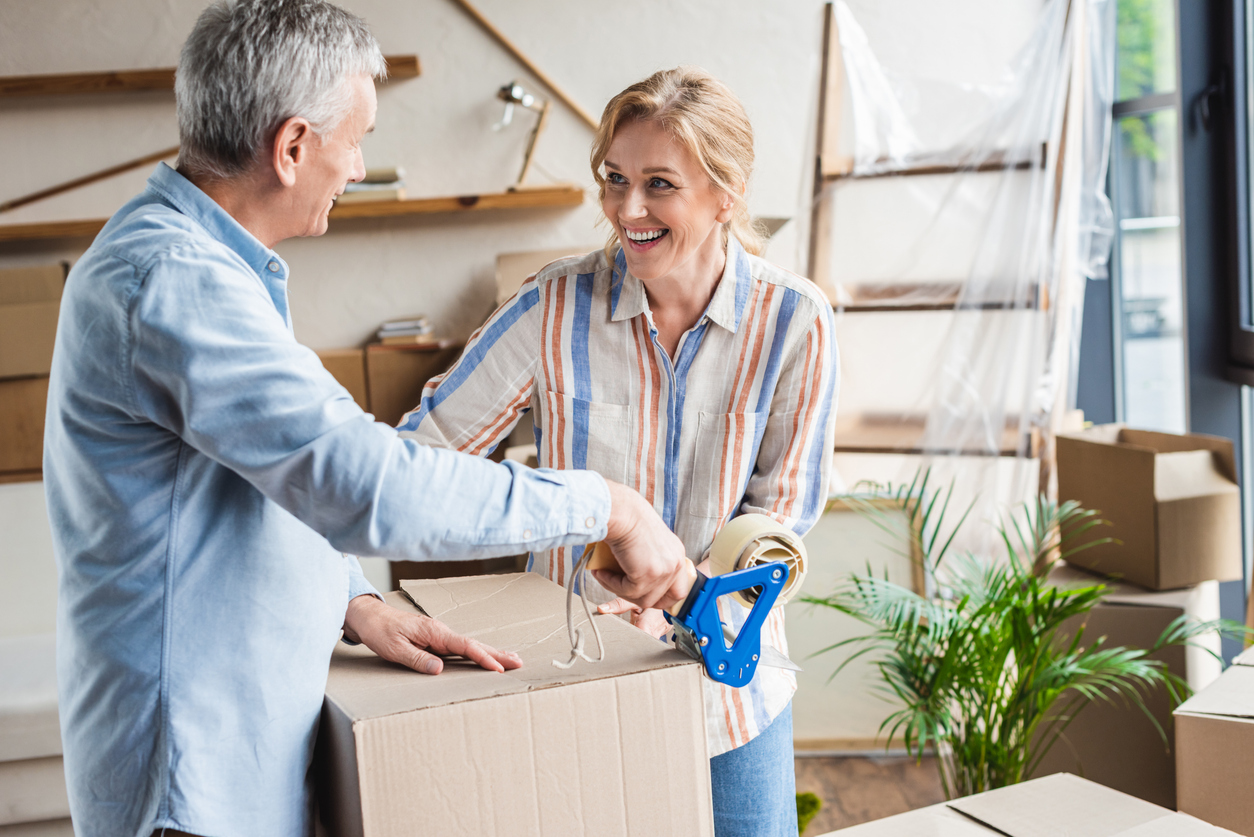 happy elderly couple packing cardboard boxes during relocation