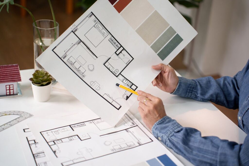 A hand pointing at a home floor plan while reviewing room layout and walking paths.