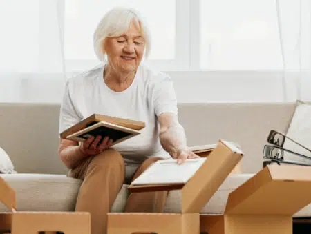 A lady places documents into a cardboard box for storage.