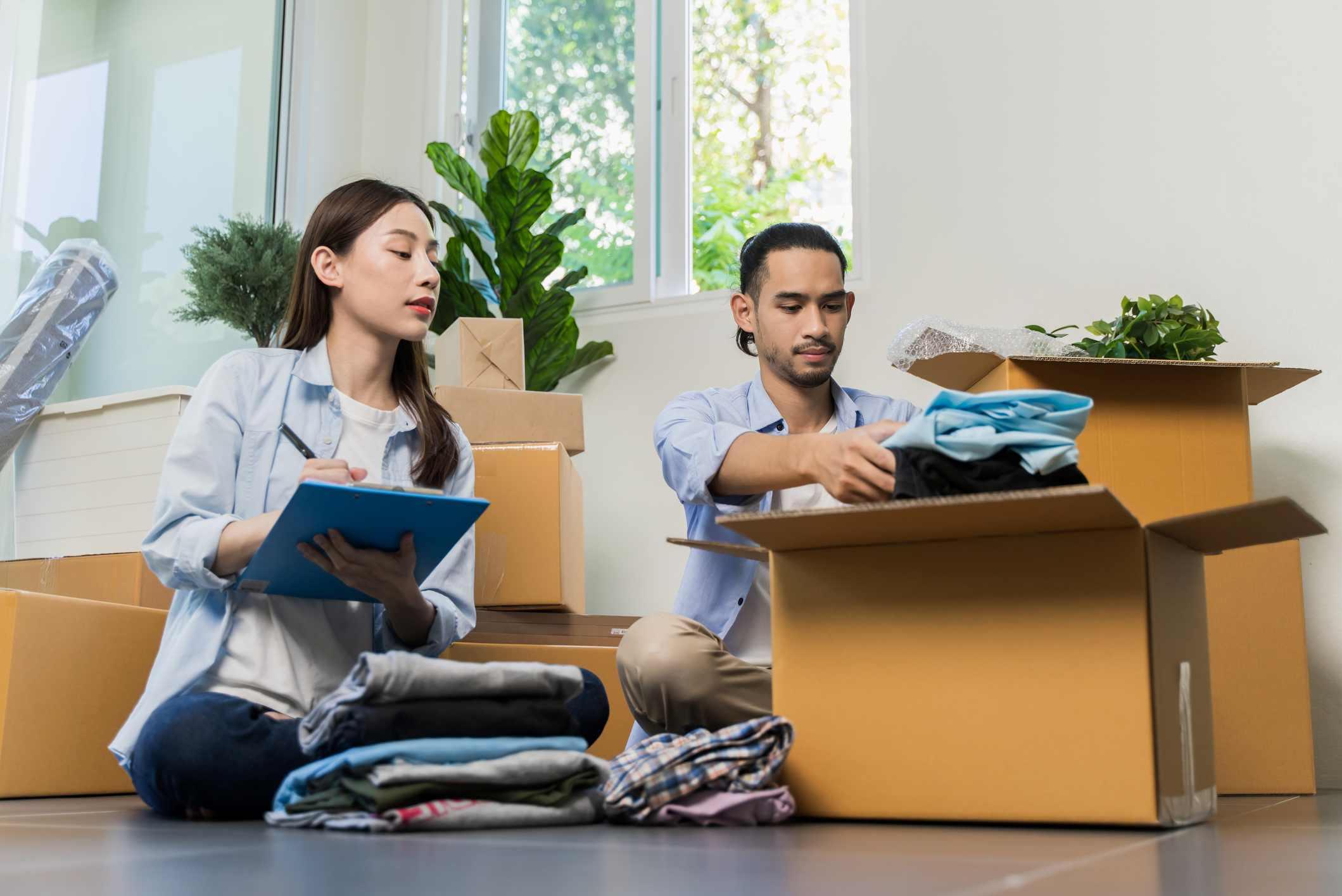 Attractive young Asian couple preparing clothes and putting into the box for giving and sharing to poor people.
