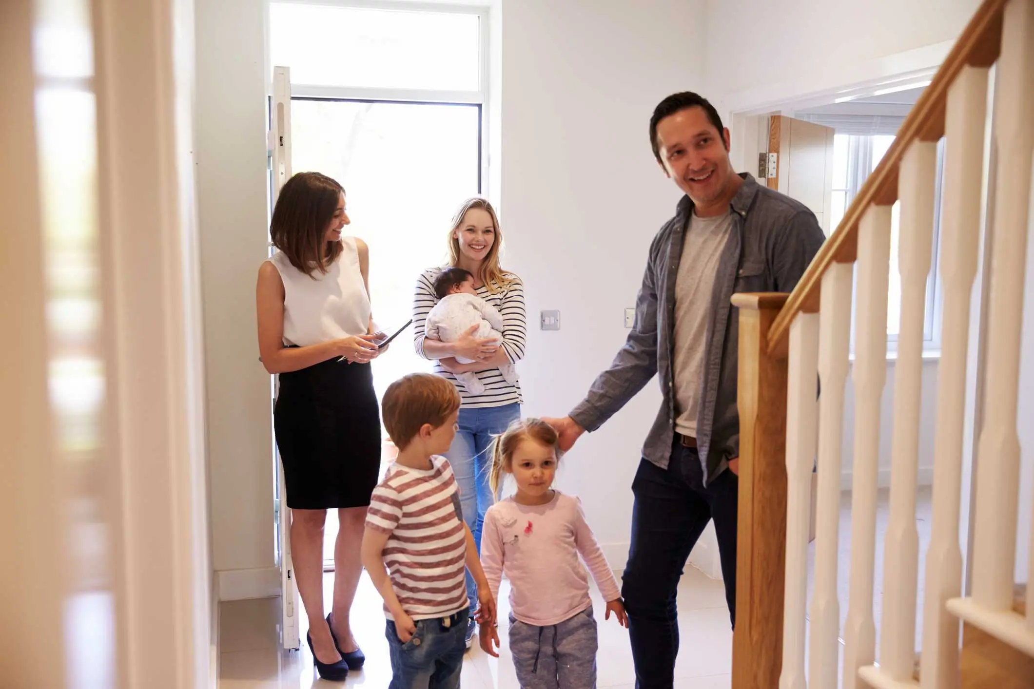 Real Estate Agent Showing Young Family Around Property For Sale