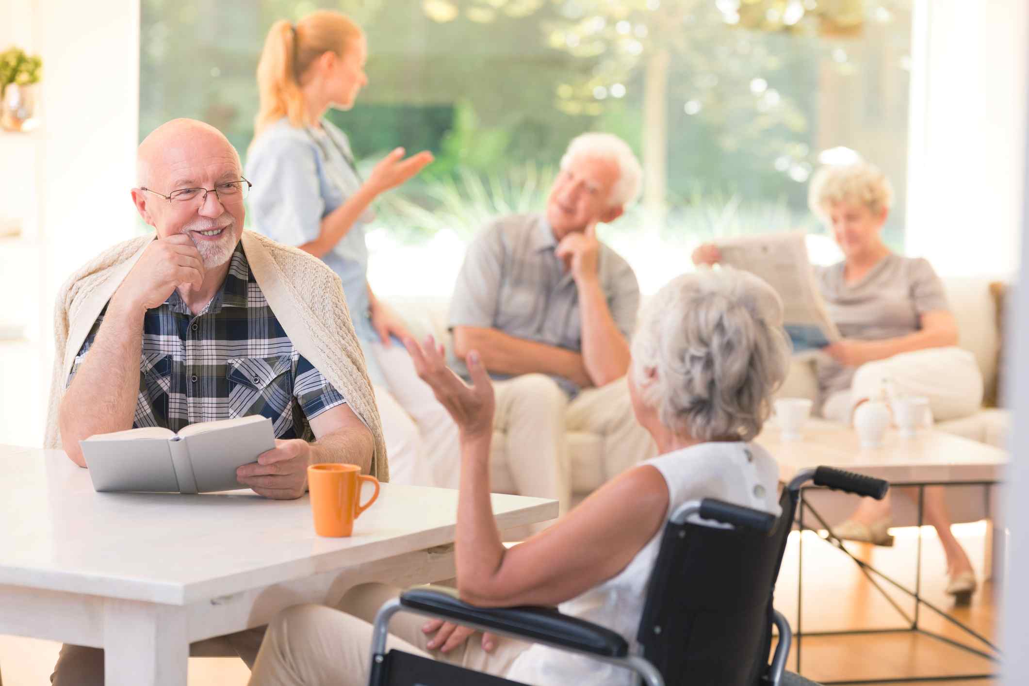 A group of seniors sits together happily in a senior living community.