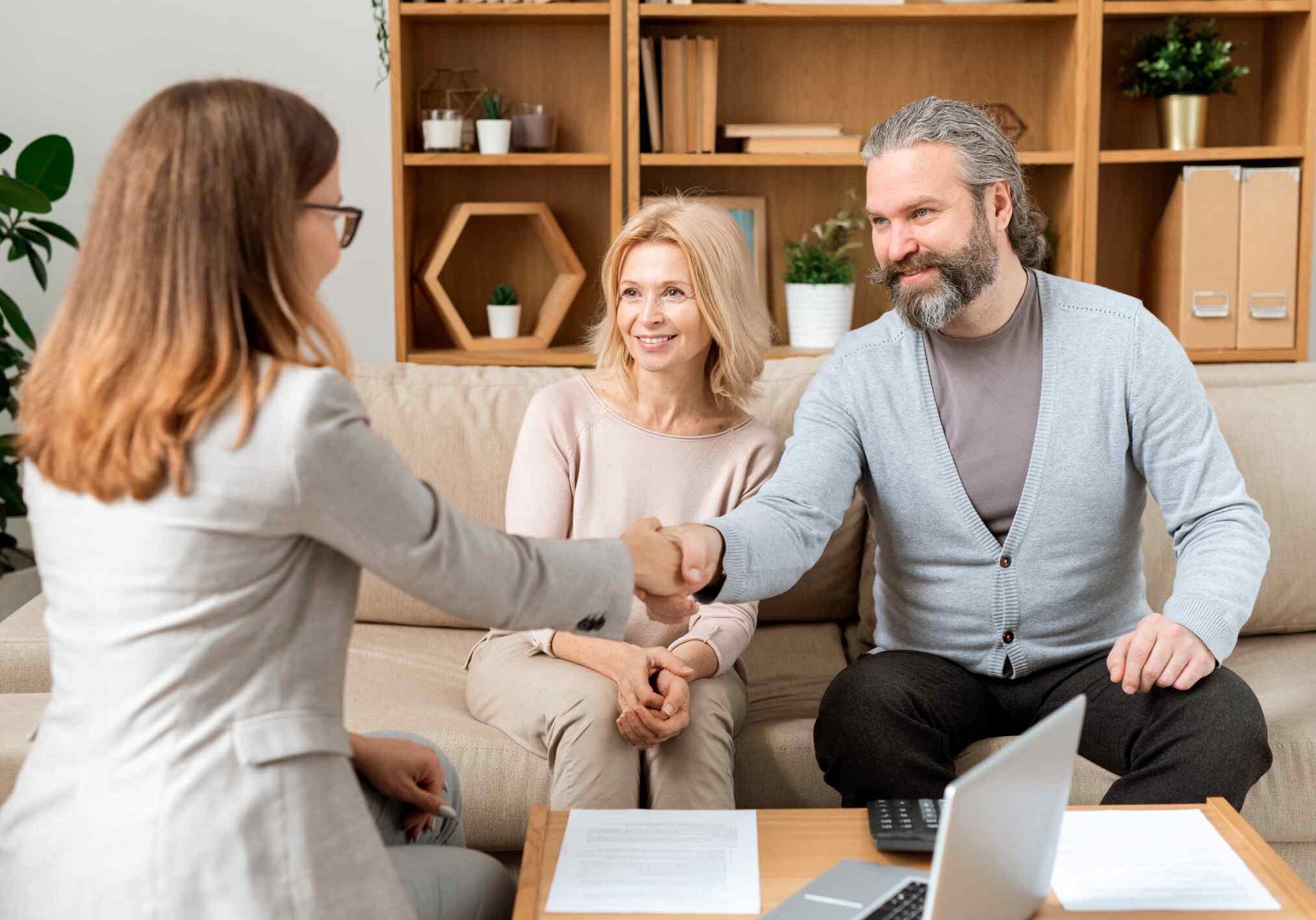 Happy mature bearded man giving hand to young real estate advisor after negotiating and signing all necessary papers