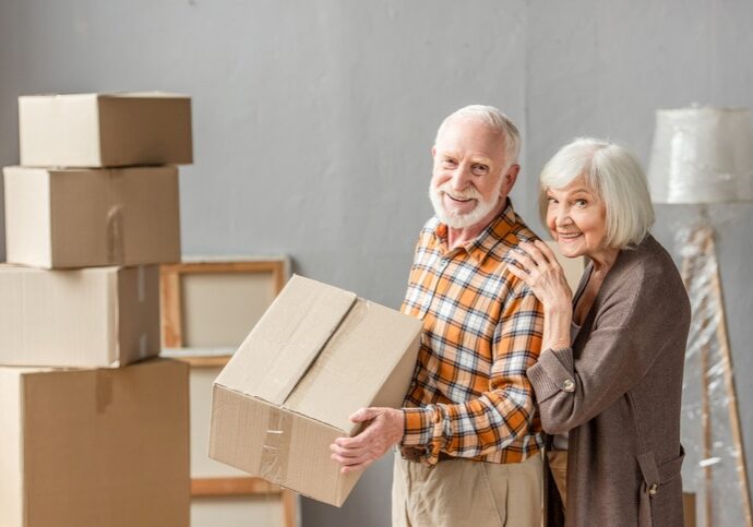 An older couple moving cardboard boxes.