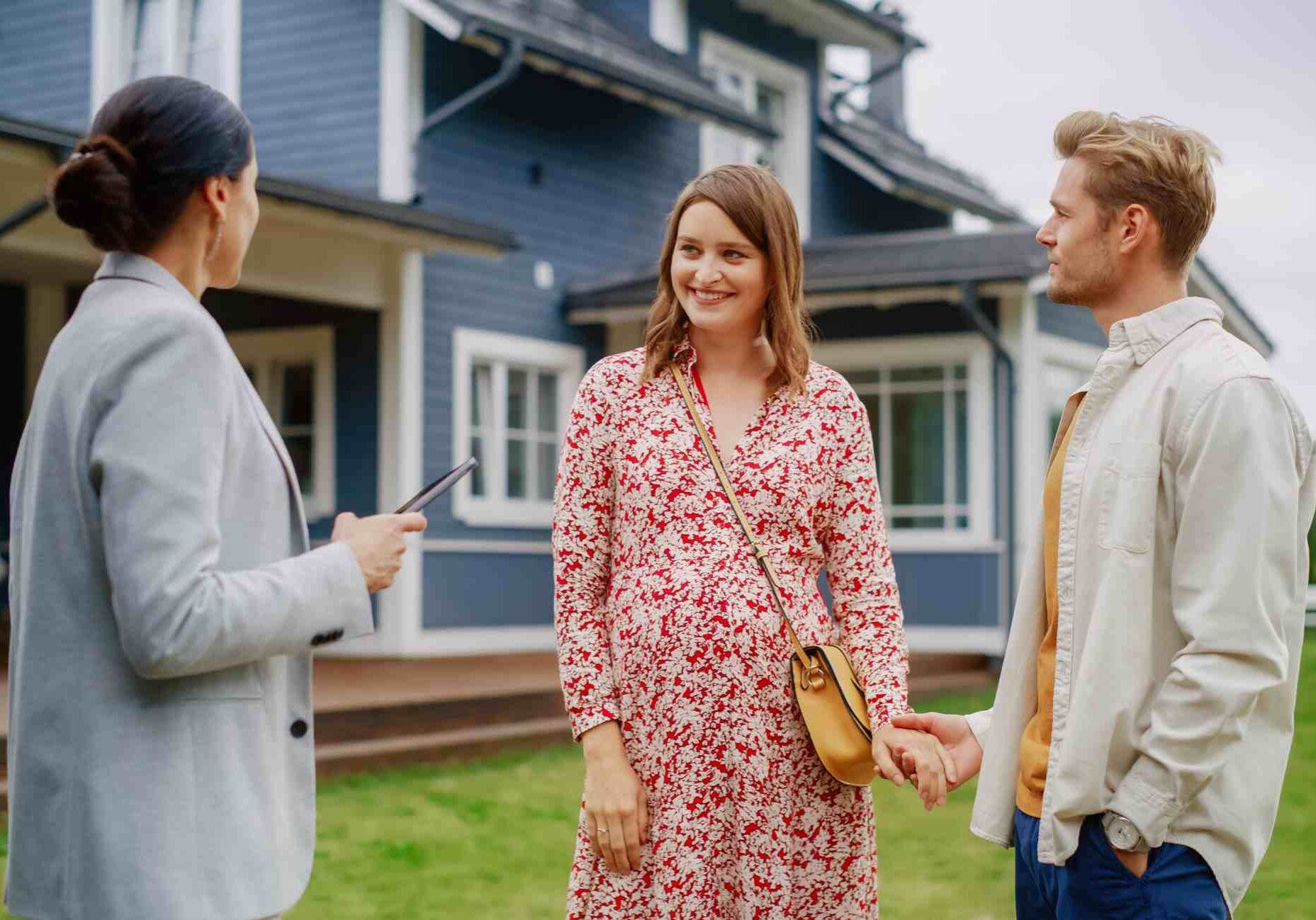 Professional real estate agent Showing a Hot Property Location to a Young Successful Couple. Female Real Estate Agent with Tablet Walking with Family to the House. New Homeowners. Slow Motion