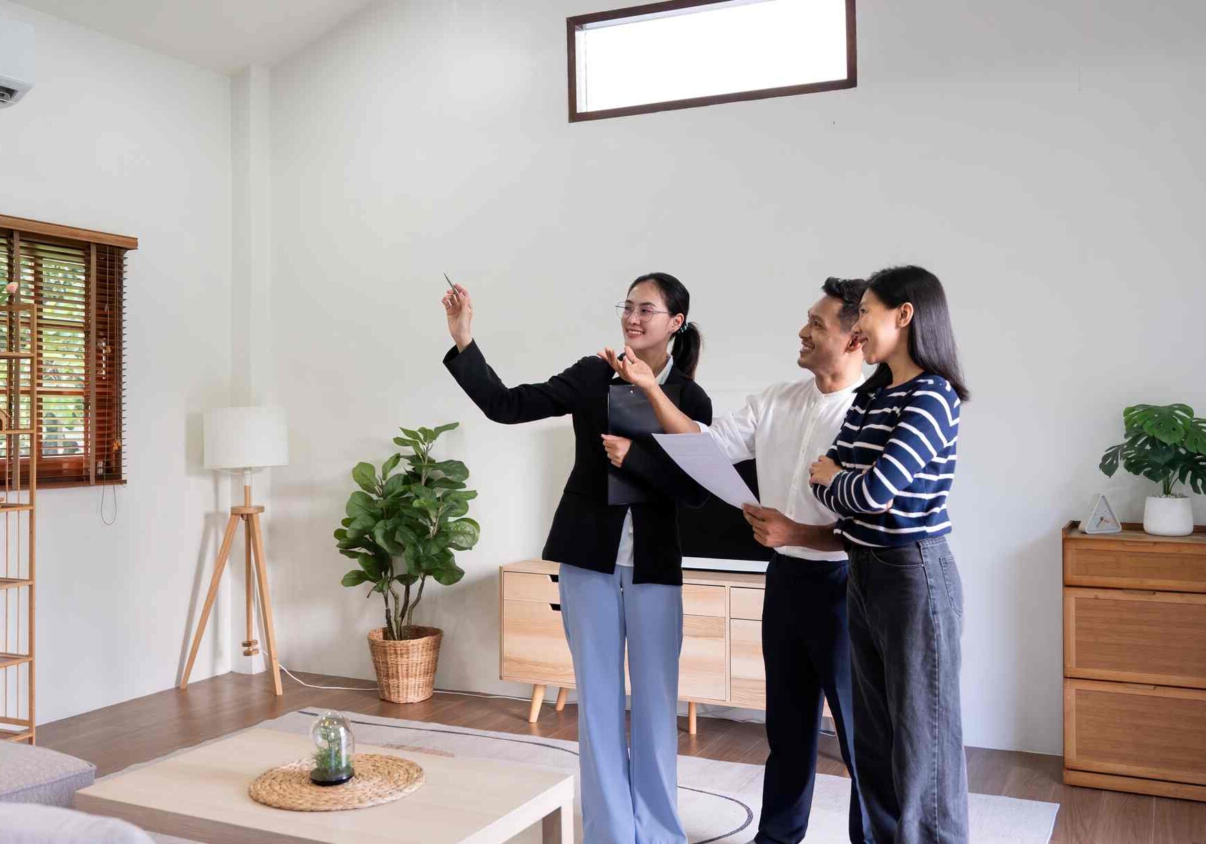 Young couple follow a real estate agent who is giving them a tour around a home, showing all the room and telling about all the advantage of living. Buying house or apartment concept.