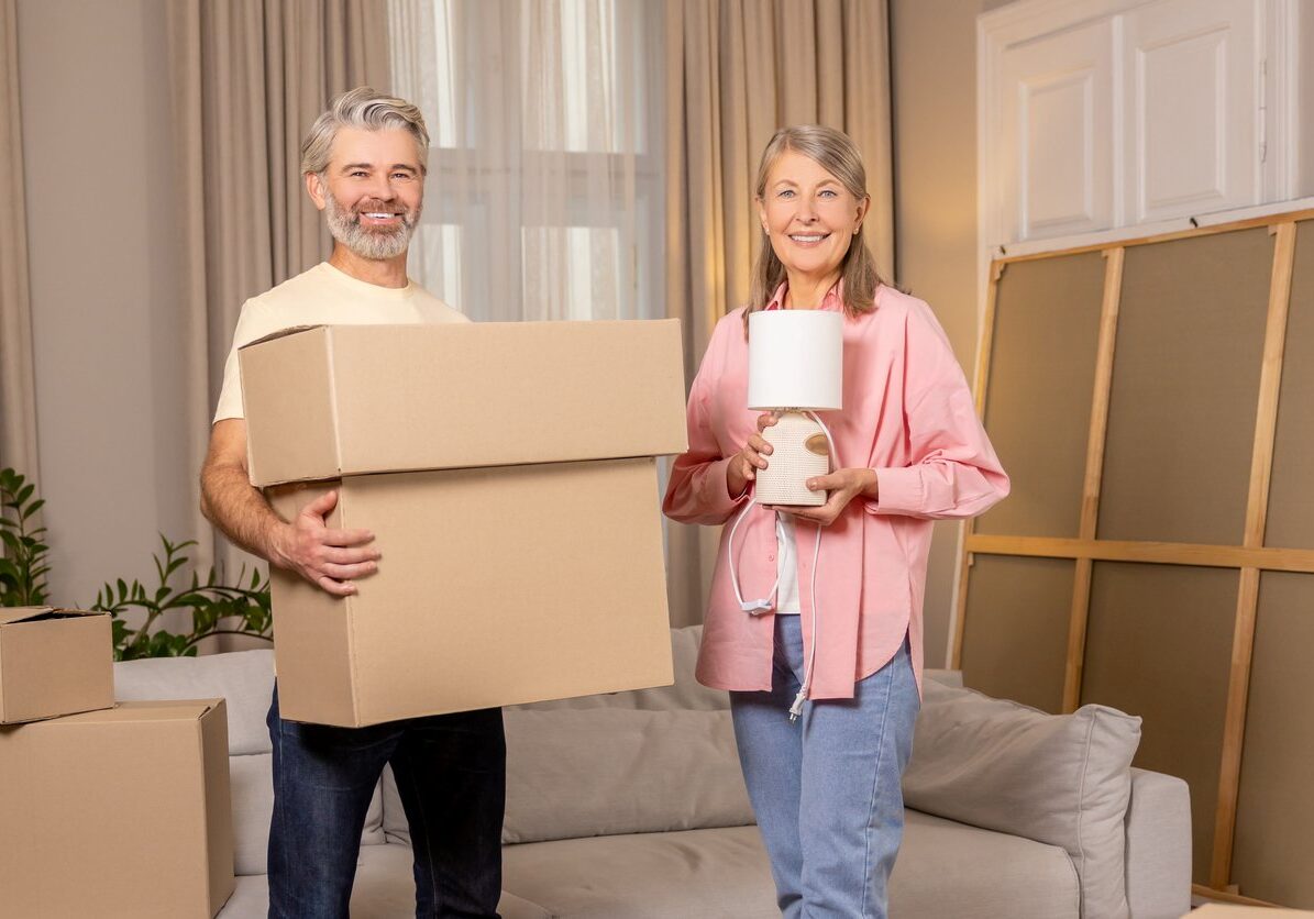 Older couple holding boxes and lamps.