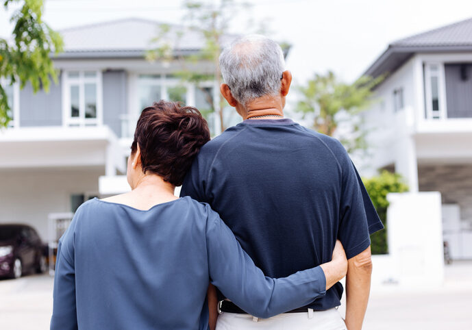 Happy senior couple from behind looking at front of house and car