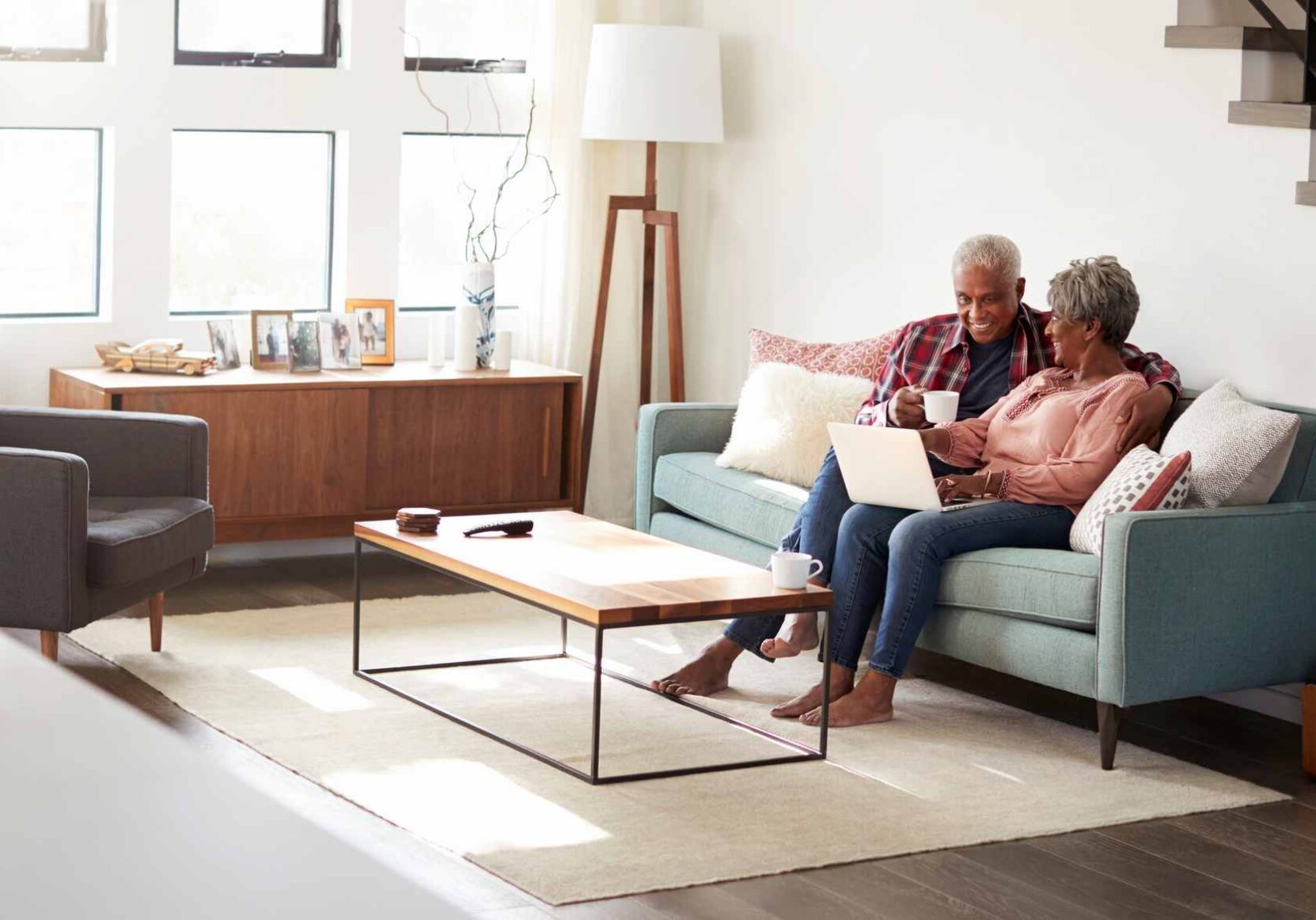 Senior Couple Sitting On Sofa At Home Using Laptop To Shop Online