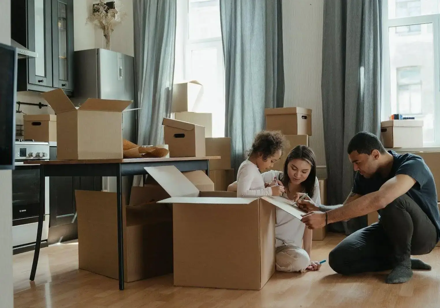 Family sits around looking at memories while packing boxes for their move.